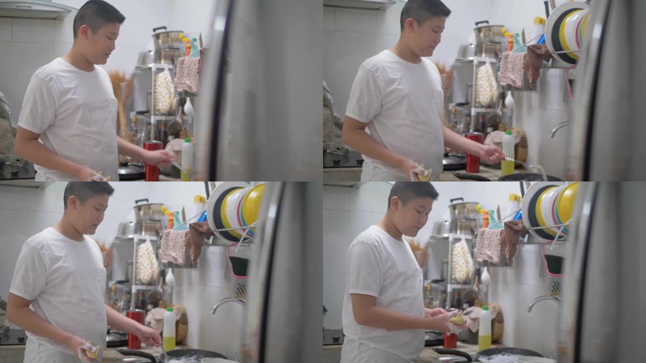 亚洲青春期男孩在家厨房洗碗，生活方式概念。
