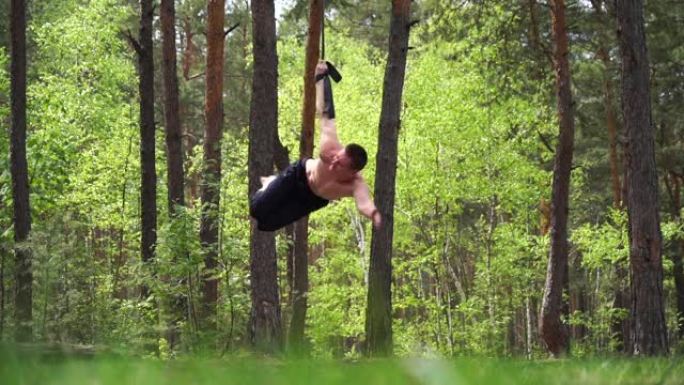 马戏团艺术家在绿色公园用空中吊带做健美操。