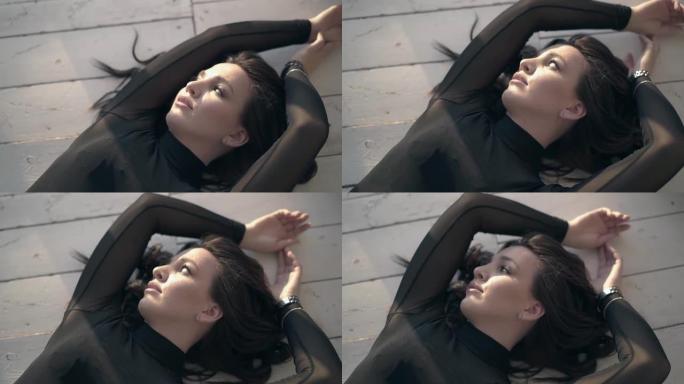 黑衣美女躺在阳光下的木地板上