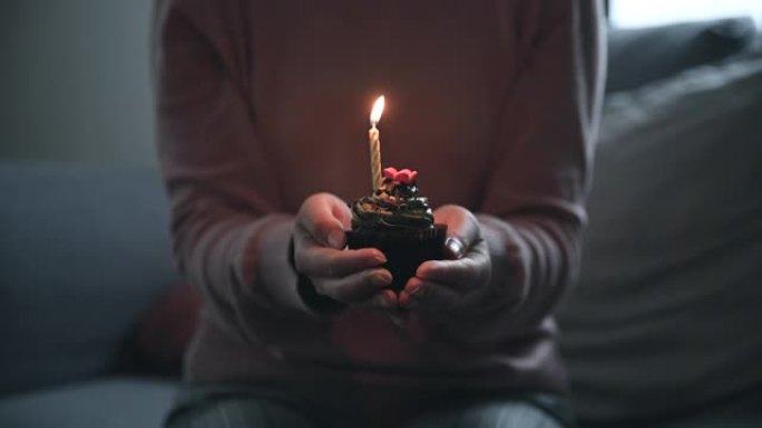 亚洲妇女通过视频通话在线虚拟聚会在家里庆祝生日，而孤立地呆在家里。手握杯蛋糕点亮蜡烛