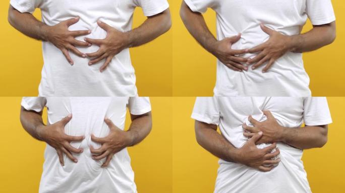 特写。男子用双手抱住他的胃，有胃炎发作或疼痛的痉挛，压在肚子上，痛苦的表情孤立在黄色的背景。