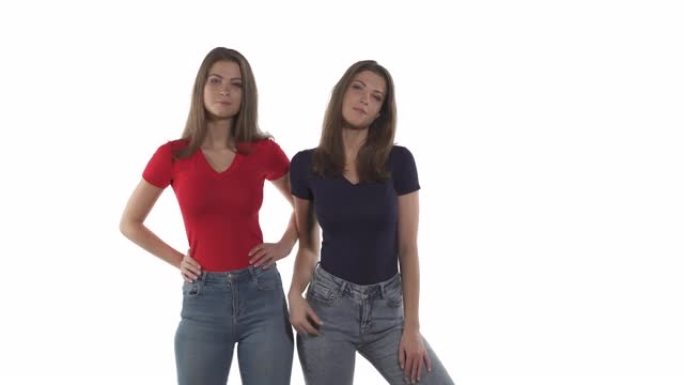 诱人的高加索双胞胎姐妹，穿着牛仔裤，红色和黑色t恤，手放在臀部摆姿势。孤立在白色背景上