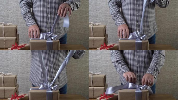 男性双手解开盒子上的一个漂亮的大弓。礼物开放概念。