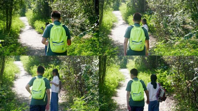 快乐的亚洲男孩和他的妹妹带着背包在阳光明媚的日子一起走在森林里，生活方式的概念。