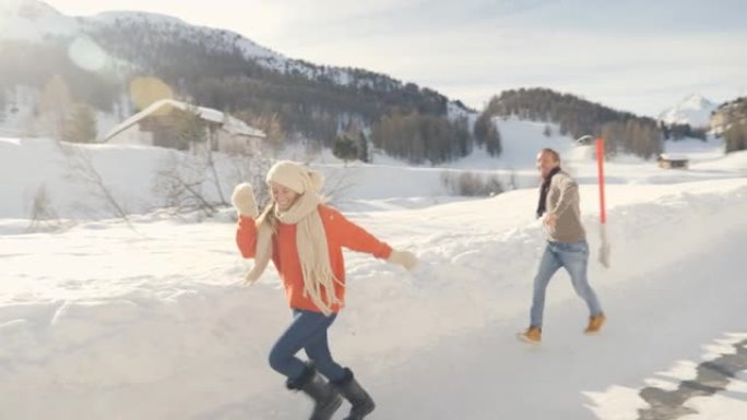 嬉戏的年轻夫妇在阿尔卑斯山的冬天互相扔雪球