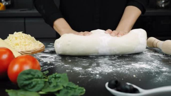 专业面包师正在揉捏酵母面团，在现代厨房制作比萨饼。为面包店用手揉糕点。准备面包的过程