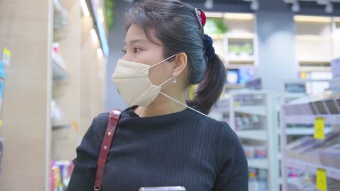 covid疫情后新常态年轻聪明的亚洲女性购物新的生活方式在超市用脸或口罩保护手选择消费品新的正常生活