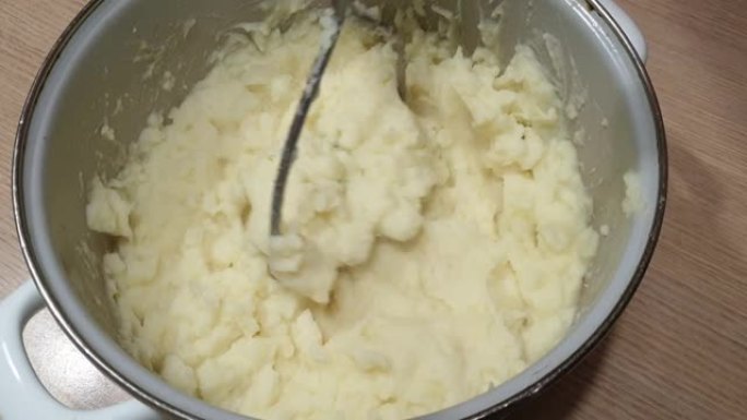在家煮土豆泥，家庭主妇在锅里把煮熟的土豆打烂