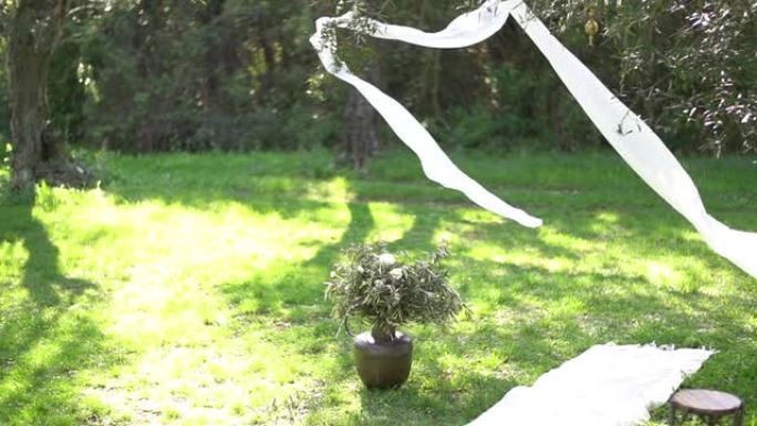 橄榄树林中的婚礼场地，装饰有飞舞的白布，烛台和毛巾走道