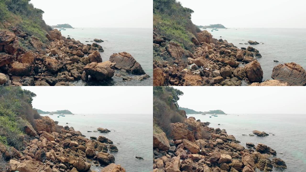 相机沿着海边散落在山脚的海滩岩石移动