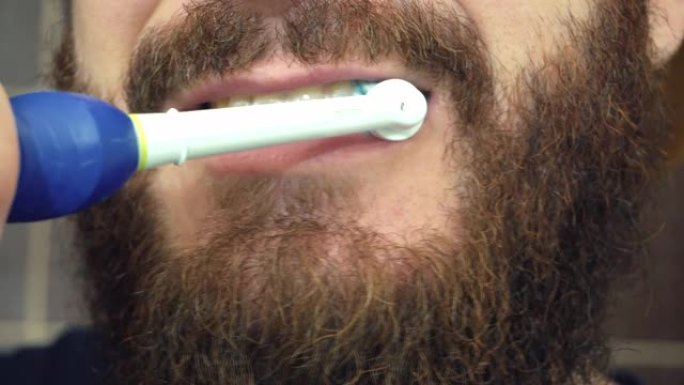 特写男子用电刷刷牙的镜头。