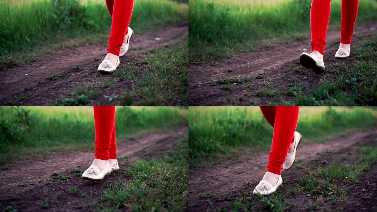 穿着红色裤子的女人穿过土路