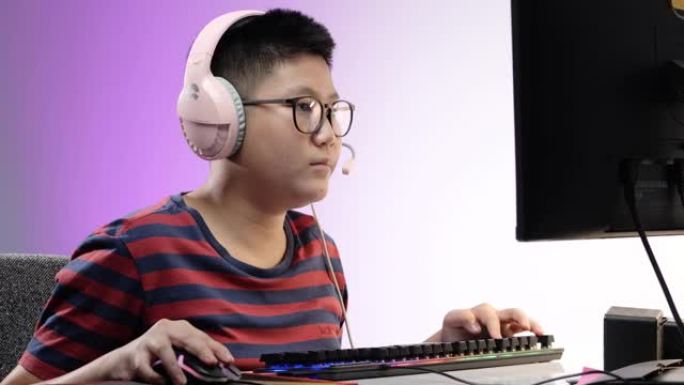 快乐的亚洲男孩在晚上在家玩网络游戏，带led灯背景，生活方式概念。