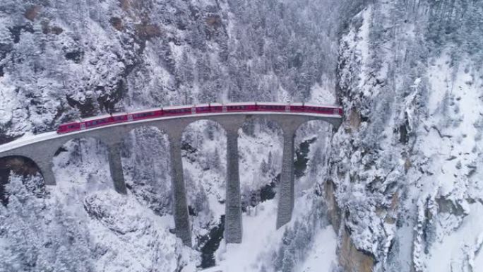 冬天有铁路和火车的Landwasser高架桥。下雪。瑞士阿尔卑斯山。瑞士。鸟瞰图。无人机向后和向上飞