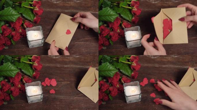 女人的手用心打开一封信。桌子上有玫瑰和蜡烛。情人节概念。