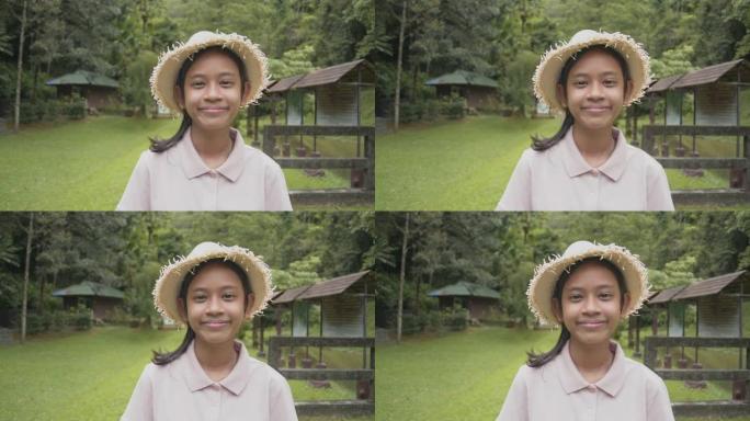 肖像亚洲年轻女孩戴着草帽在森林公园快乐地微笑。女性青年志愿者向导站在草坪上迎接热带森林的游客。