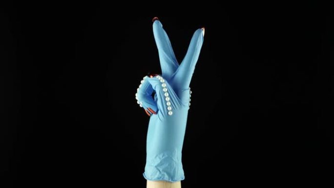 女人手腕手和胜利象征。交出蓝色医疗装饰手套PPE。一次性手术防护手套中的女性手掌。概念战与COVID