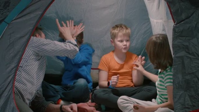 男子在儿童营地的帐篷里扮演儿童。他们用手点击玩得开心