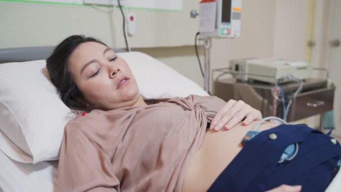 亚洲孕妇担心产前超声扫描。女性佩戴婴儿胎儿监护仪腰带在怀孕期间感到抑郁。