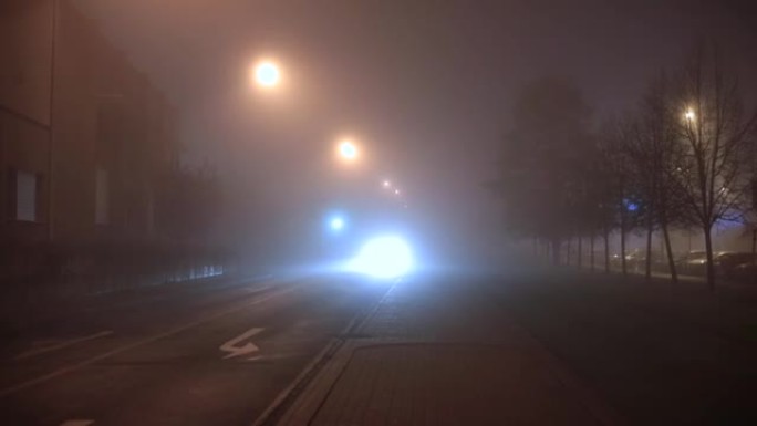 前灯照亮车辆的路径。雾蒙蒙的夜晚。