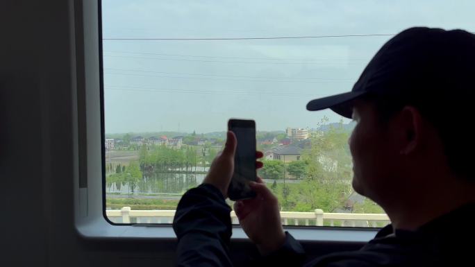 高铁上拿手机拍风景的人