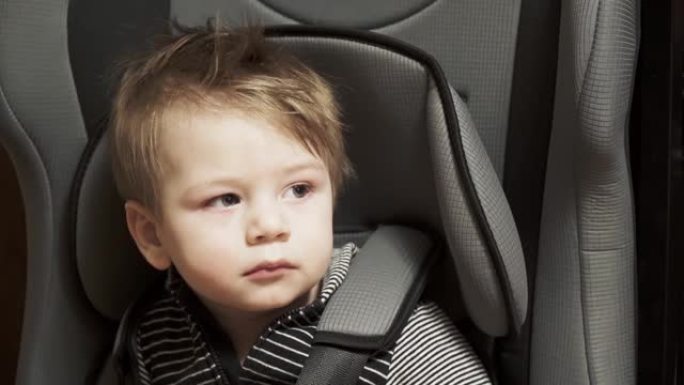 男婴坐在汽车上的儿童座椅上