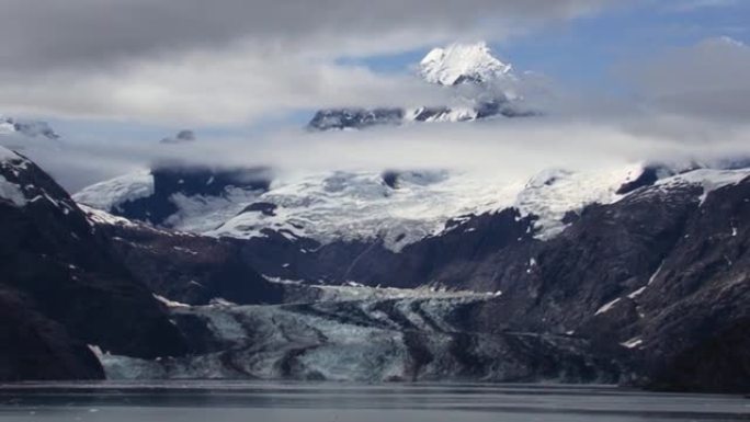 约翰·霍普金斯冰川及其周围的白雪皑皑的山脉和云。阿拉斯加的冰川湾景观。