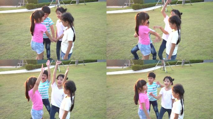 一群快乐的年轻亚洲儿童在夏天在城市公园游乐场外面堆放或堆放双手。儿童和娱乐概念。