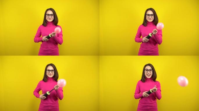 一名年轻女子用黄色背景上的泵给一个粉红色的气球充气。穿着粉色高领毛衣和眼镜的女孩。