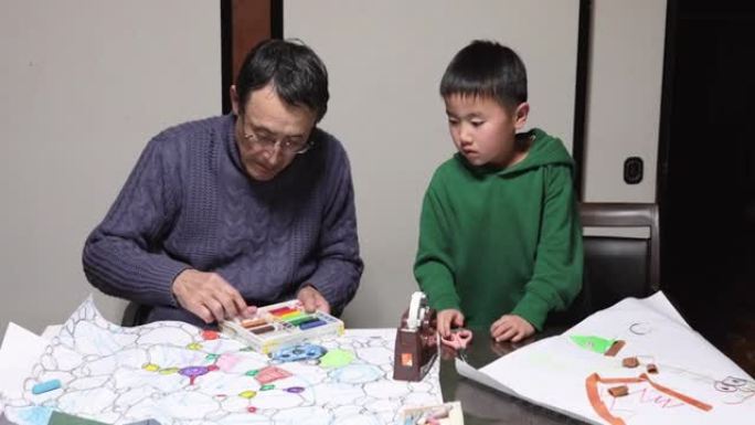 亚洲高级男子和孙子一起在家制作手工艺品