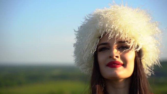 穿着白色木瓜和红色民族服装的格鲁吉亚女孩在绿色的田野上行走和微笑。视频肖像。格鲁吉亚文化生活方式。