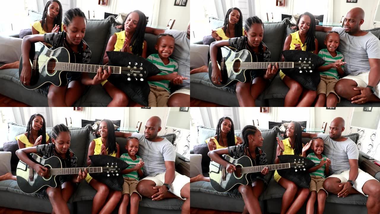 休闲的非洲家庭坐在家里的沙发上，黑人女儿演奏吉他器乐