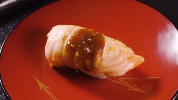 寿司配米饭，烤猪肉和酱汁放在转盘上。日本料理与微距拍摄。