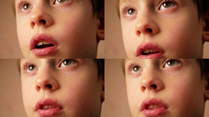 一个6-7岁的高加索男孩的特写脸惊讶地张开了嘴。这个孩子专心和钦佩地看电视。情绪化的孩子。选择性聚焦
