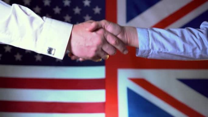 在两国国旗的背景下，美国和英国之间的握手。