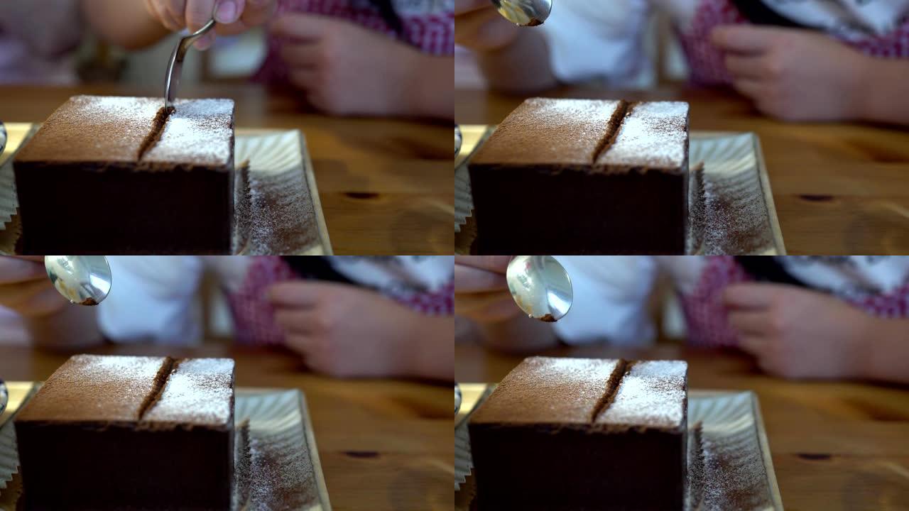 小女孩在餐馆吃甜点。盘子上巧克力蛋糕的特写。主题在左边。