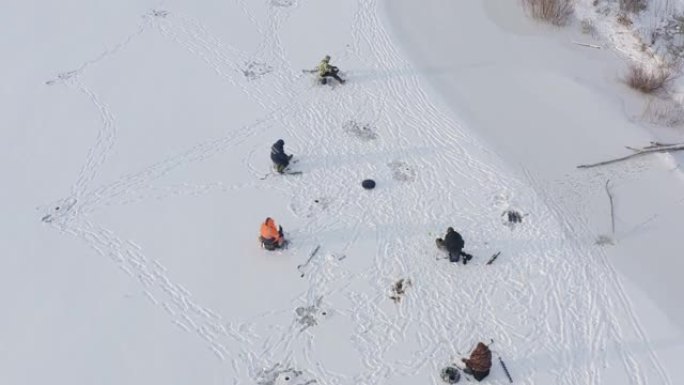 冬季捕鱼的概念: 渔民在冰洞附近的冰上定居。钓鱼竿躺在冰上。在晴朗的寒冷天气钓鱼。极寒天气服装概念。