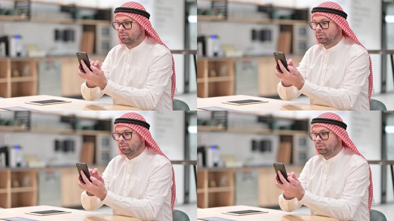年轻的阿拉伯男子在办公室使用智能手机