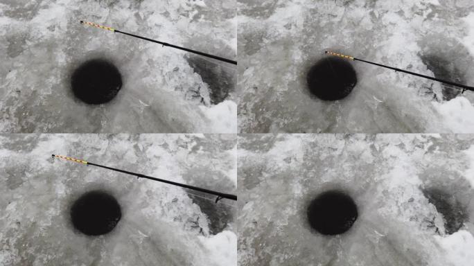 冬季钓鱼的钓鱼竿被困在一个洞中