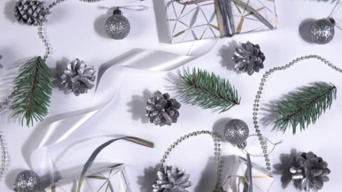 圣诞抽象背景360度旋转。白色背景上旋转的银松果、冷杉树枝和礼品盒