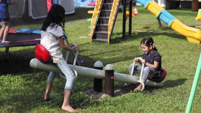 泰国小孩在操场玩跷跷板。