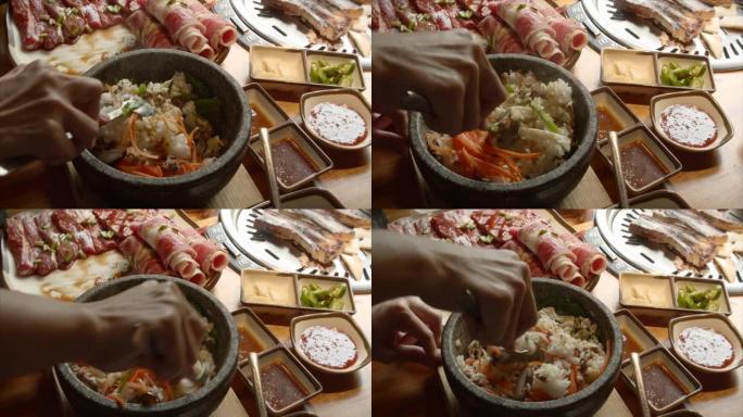 厨师用铸铁锅煮米饭，小心地将米饭与切成薄片的胡萝卜，菠菜，小麦根混合在桌子上，一个开胃的美味牛排，切