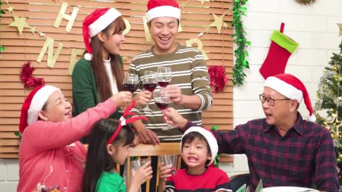 东南亚多代家庭的时刻，微笑着，快乐地围着一张可爱的桌子，在圣诞节的美食晚宴上，一起用红酒杯欢呼，而孩