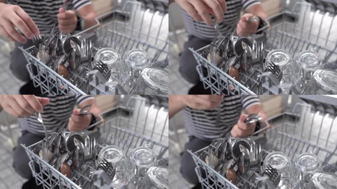 男人用手从洗碗机上取下干净的叉子和勺子。