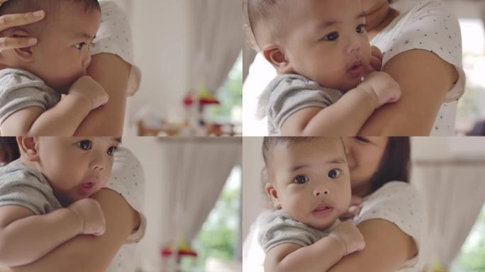一个亚洲男婴和他年轻美丽的母亲抱着他在家里的客厅里温暖的爱和关怀。