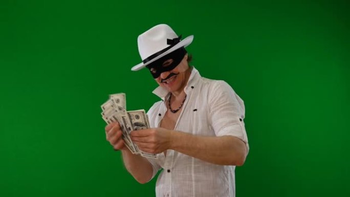 戴着黑色面具和白色帽子的迷人骗子在绿色背景上享受金钱和诱惑。