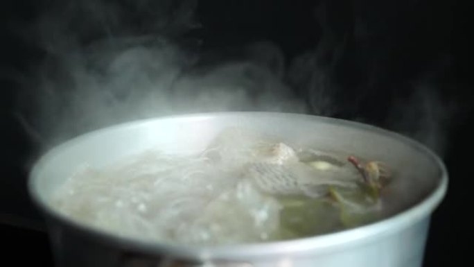 泰国菜，在厨房煮辣鱼汤，白烟和黑色背景上的蒸汽效果。文化旅行和烹饪概念。