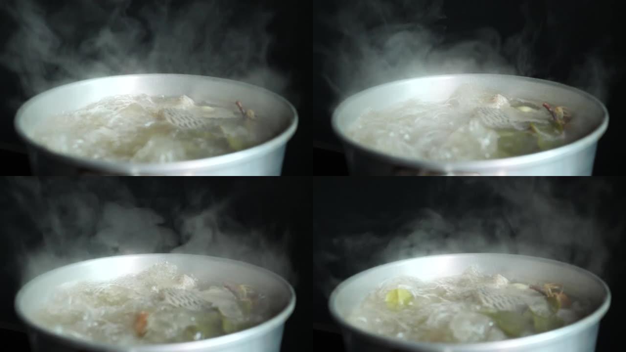 泰国菜，在厨房煮辣鱼汤，白烟和黑色背景上的蒸汽效果。文化旅行和烹饪概念。