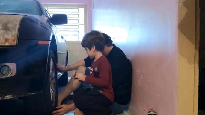 父子俩在车库里换汽车轮胎。