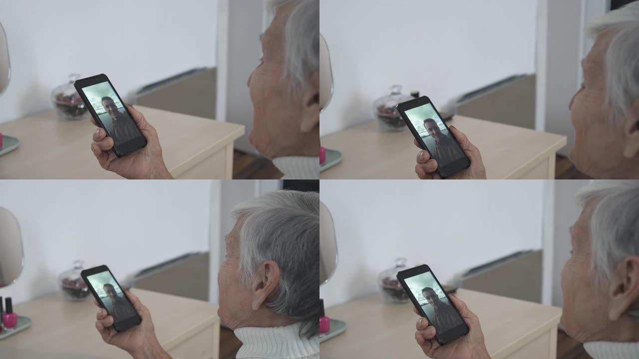 老妇人在家使用智能手机进行视频聊天，与孙子聊天，享受手机上的对话分享生活方式
